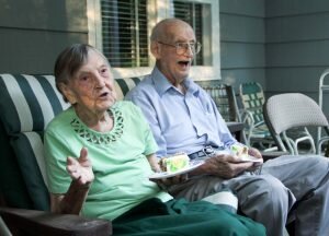 Luella Ostrofsky speaks to partygoers while Henry Scott “Bud” McQuade listens on the front porch of Ostrofsky’s newly painted home in Easton — Mev McMahon photo